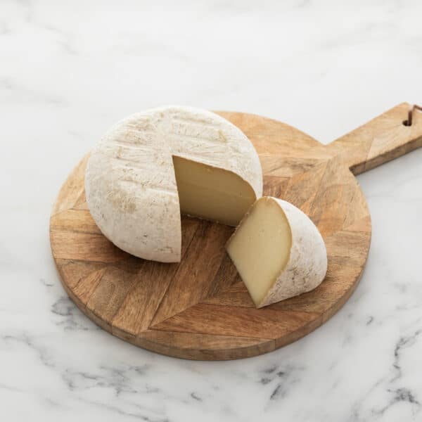 Sharpham Washbourne whole cheese, cut with a wedge pulled out so you can see paste and rind of cheese
